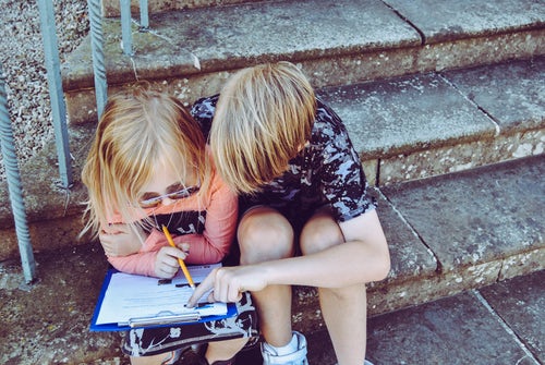 two children sitting on a step doing homework